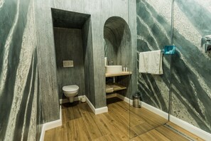 Une salle de bain avec un plancher en bois, des toilettes, un lavabo et une douche à parois de verre.