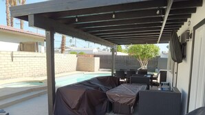 A covered patio area with a pool, outdoor furniture, and a barbecue grill. - Located in the heart of Palm Desert (Palm Desert)