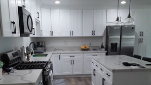 A modern kitchen with white cabinets, stainless steel appliances, and a wooden floor. - Located in the heart of Palm Desert (Palm Desert)