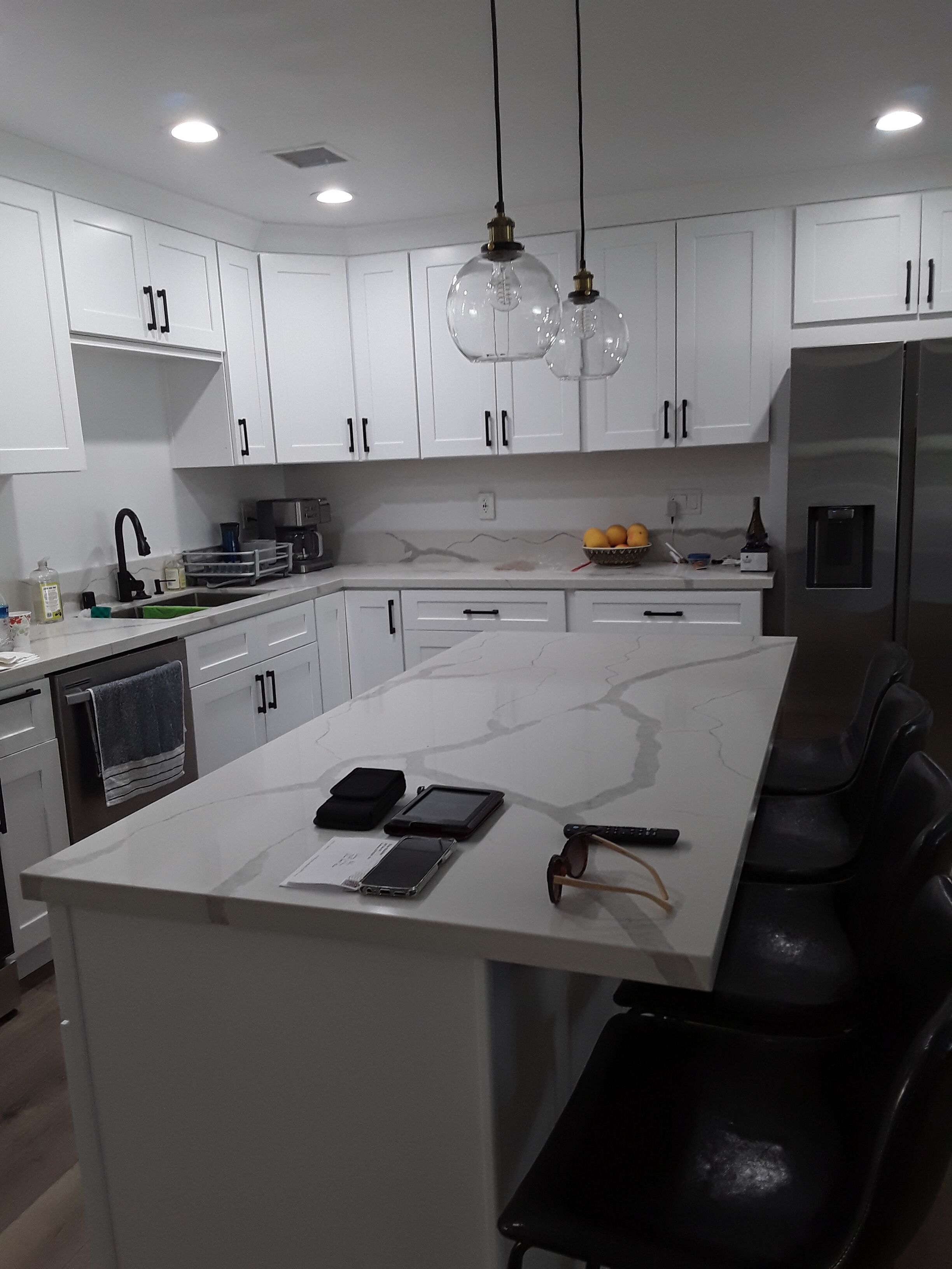 A modern kitchen with white cabinets, a marble countertop, and a built-in island with seating.