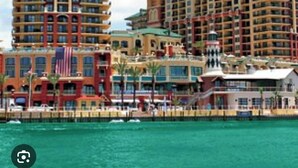 Un hotel sul lungomare con diversi edifici alti, una bandiera e un molo.