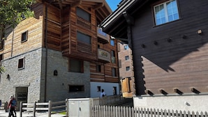 A multi-story building with a mix of stone and wood exterior, featuring balconies and large windows. - Central Zermatt studio for 2 with Matterhorn view, near lifts & restaurants (Zermatt)