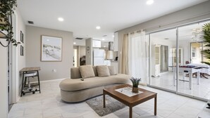 Ein modernes Wohnzimmer mit einer Couch, einem Couchtisch und einer Glastür zum Essbereich.