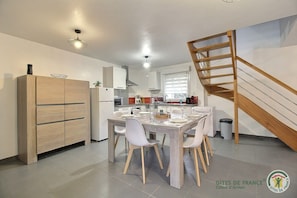Una cocina moderna con comedor, armarios de madera y una escalera.