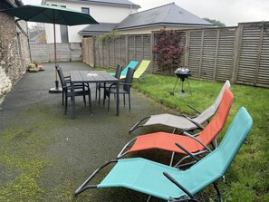 Relax outdoors with a barbecue grill and comfortable seating under a shaded area.