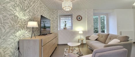 A modern living room with a sofa, TV, and decorative items.