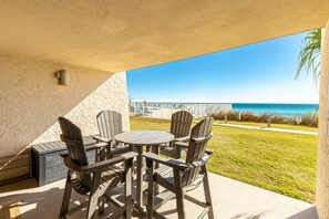 Eine Terrasse mit Tisch und Stühlen, Blick auf den Ozean und eine Rasenfläche.