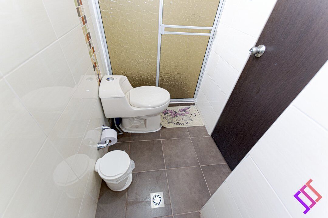 A small bathroom with a toilet, a shower, and a door.