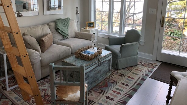 A cozy living room with a sofa, armchair, coffee table, and a ladder.