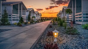 Ein Weg, der zu einer Reihe moderner Gebäude führt, mit einem Sonnenuntergang im Hintergrund.