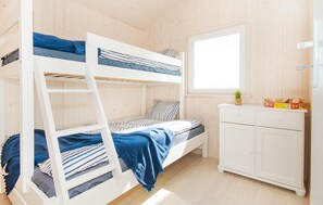 A bunk bed room with a window, a small cabinet, and a plant.