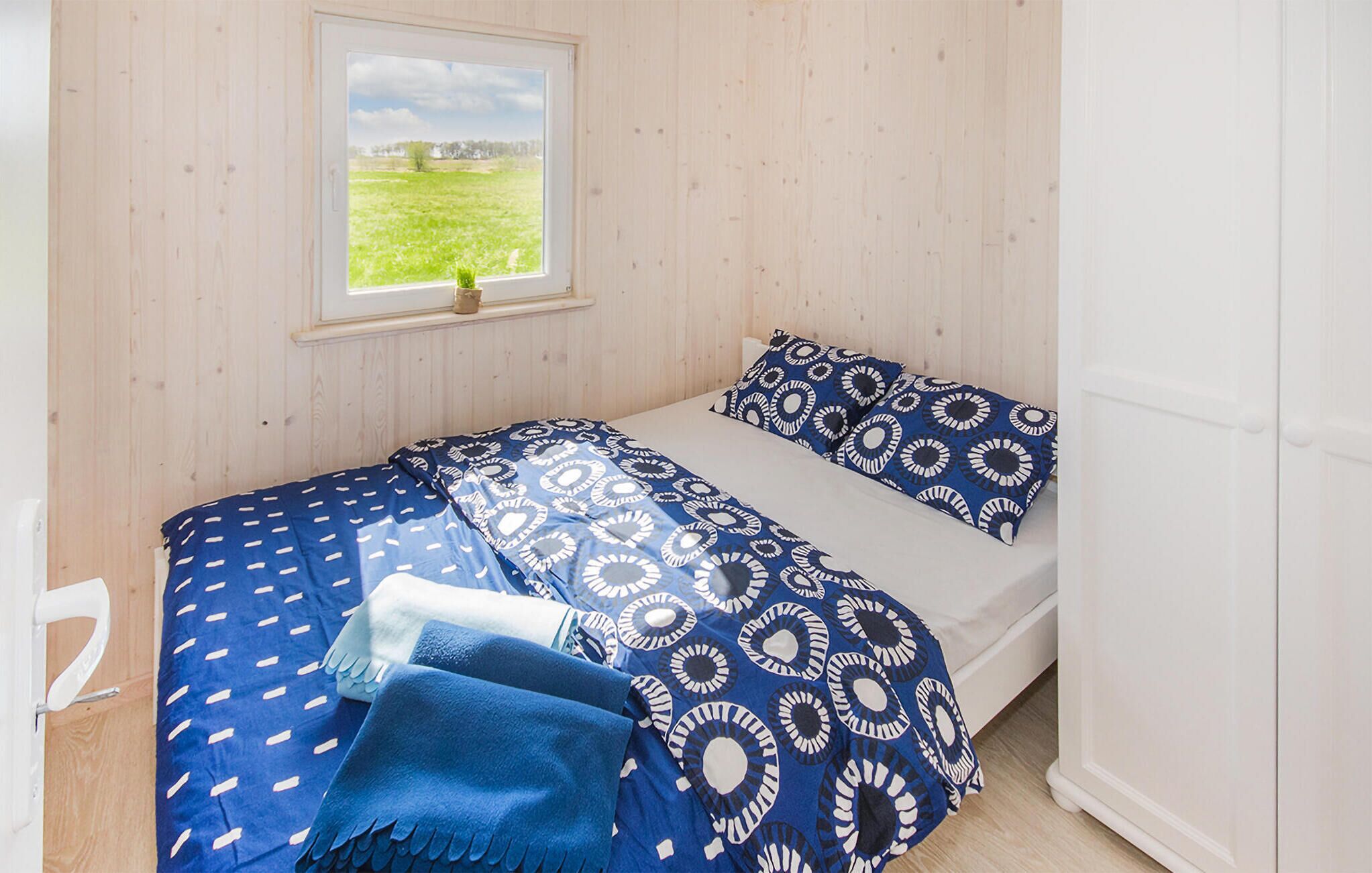 Une chambre à coucher avec un lit, une fenêtre donnant sur un champ verdoyant et des murs en bois.