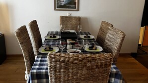 Une table à manger entourée de chaises en osier, un tableau encadré représentant le Cervin, et une lampe noire suspendue au-dessus.
