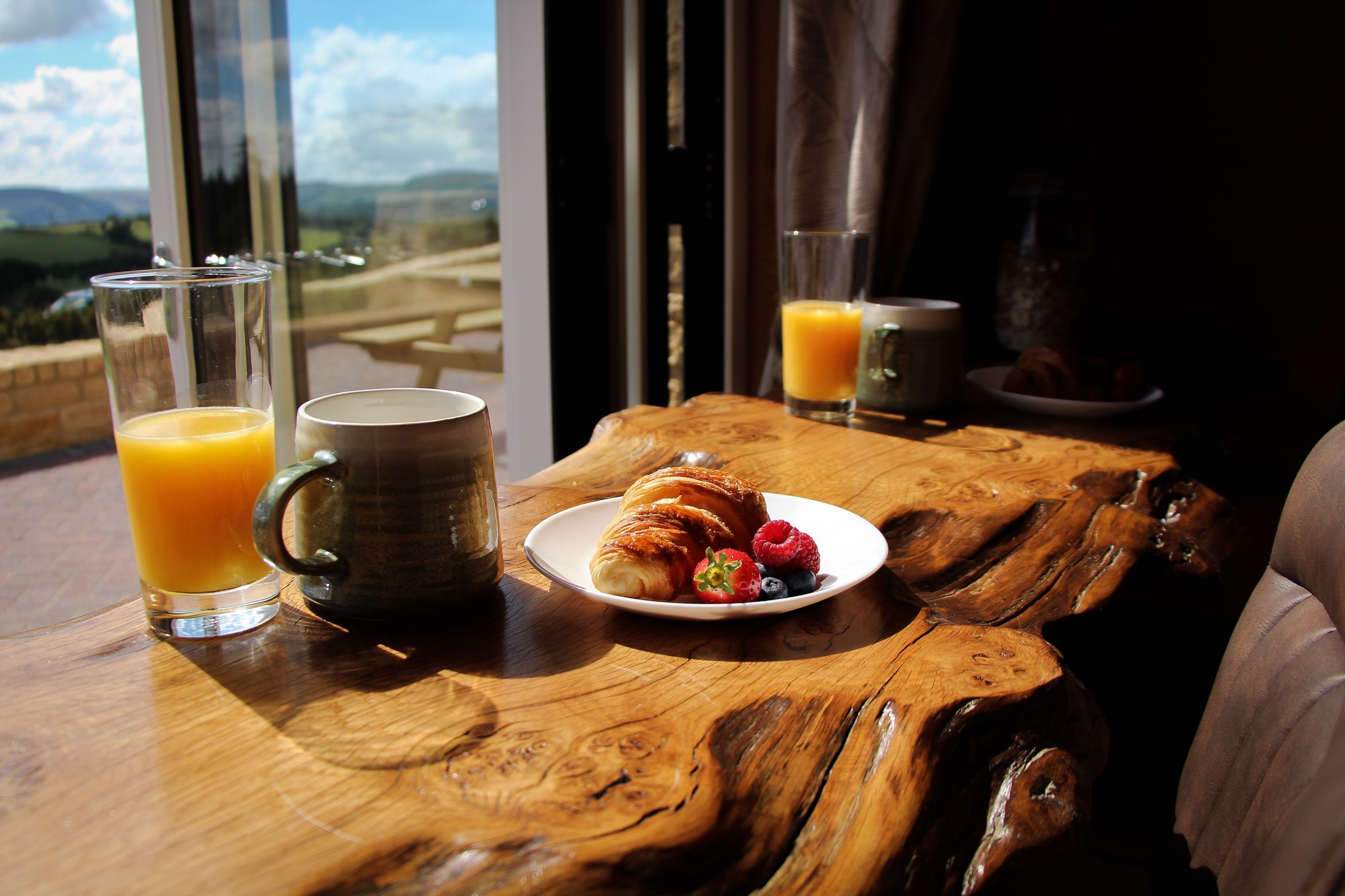A breakfast table with a croissant, berries, and orange juice glasses.