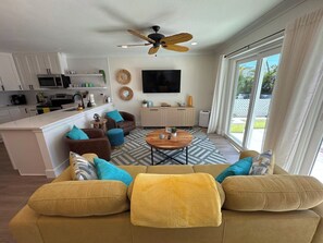 A modern living room with a sofa, coffee table, and a TV mounted on the wall.