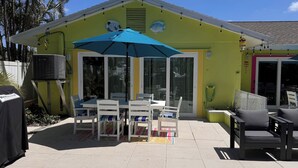 Eine Terrasse mit Tisch, Stühlen und einem blauen Sonnenschirm sowie einer Klimaanlage.