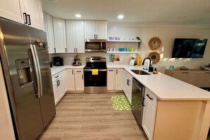 A modern kitchen with stainless steel appliances, white cabinetry, and a central island.