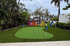 A miniature golf course with colorful chairs and a putting green.