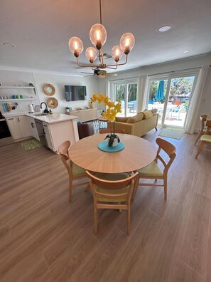 Une cuisine moderne avec un coin repas, un plancher en bois et un lustre.