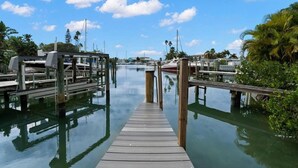 A wooden dock leading into calm water with boats docked on the right.