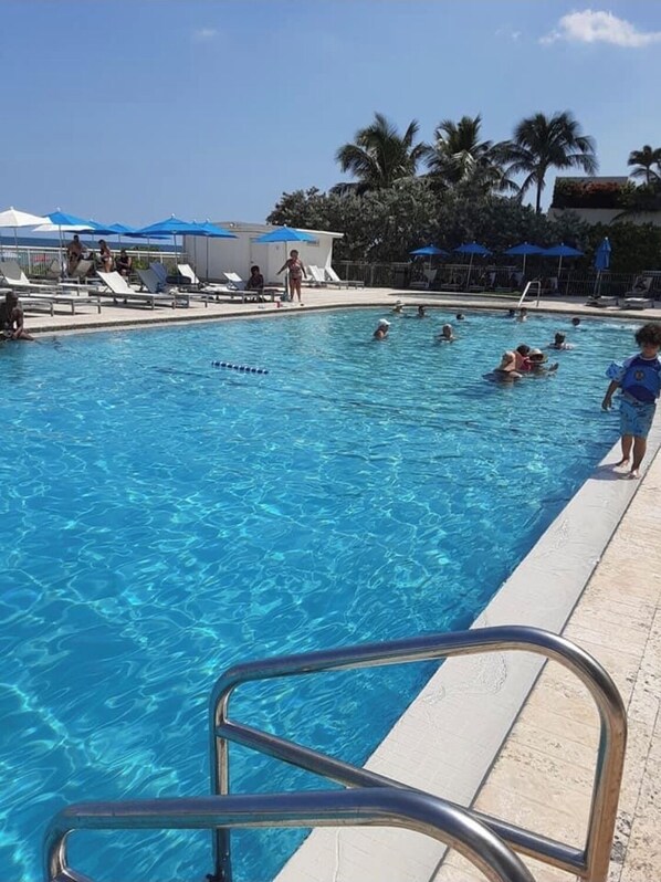 Relax by the pool surrounded by palm trees and lounge chairs.