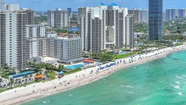 Un paysage urbain côtier avec de hauts immeubles, une plage et un ciel bleu dégagé.