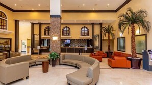 Un hall d’entrée spacieux avec un espace salon aux lignes courbes, un comptoir d’accueil et un téléviseur.