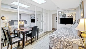 A hotel room with a bed, a desk with chairs, a TV, and a mirror. - Walk to beach, updated 2/2 condo sleeps 6, in & outdoor pools, tennis, courtyard (Hilton Head Island)