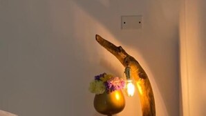 A bedroom with a bed, a nightstand with a lamp, and a wall-mounted light fixture. - Hotel Dorado san luis (San Luis)
