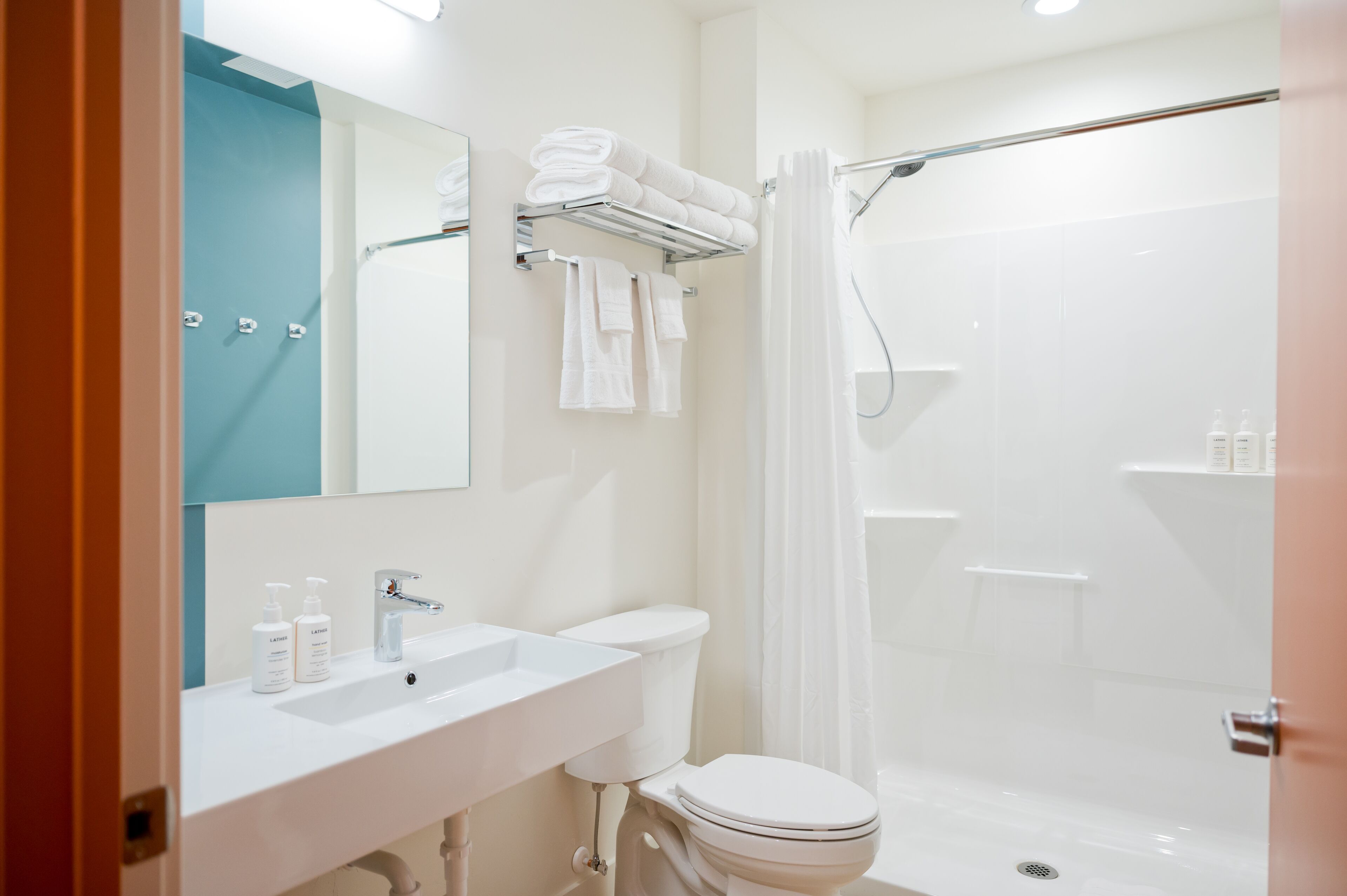 Un baño moderno con lavamanos, inodoro y zona de ducha blancos.