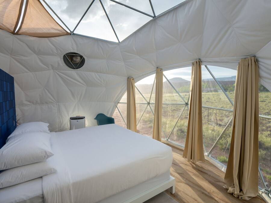 Une chambre à coucher avec un lit, un mur bleu, une fenêtre et une vue sur l’extérieur.