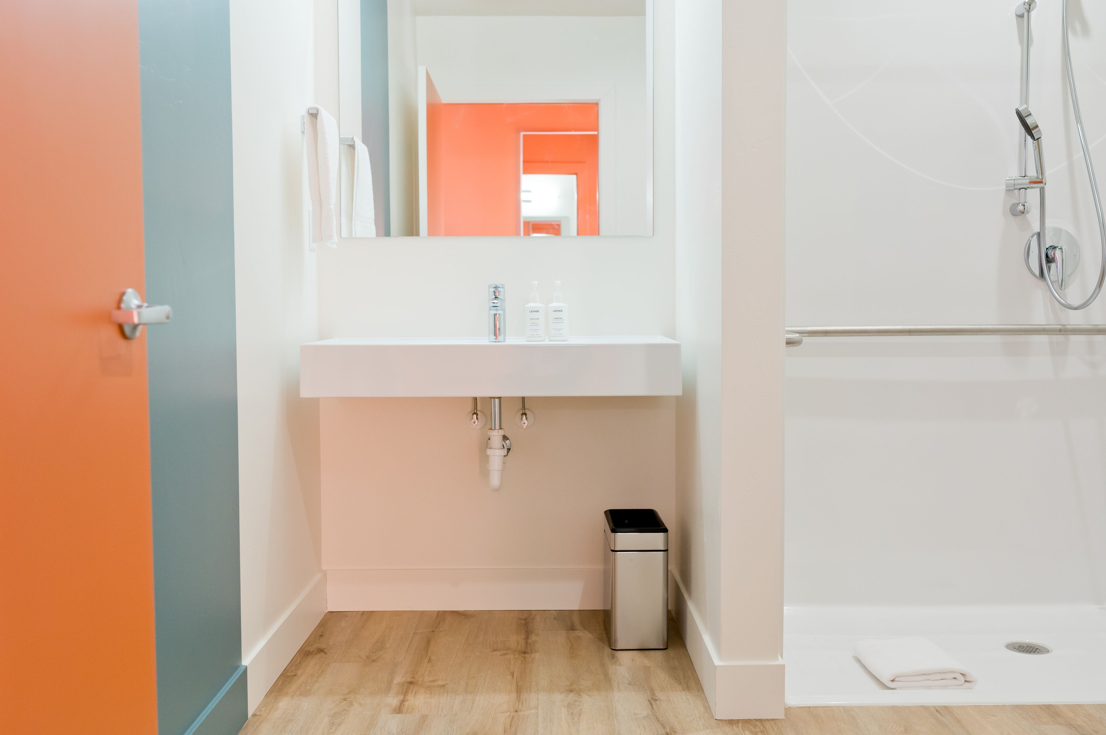 Un baño con lavamanos, espejo y ducha blancos.