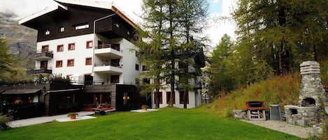 A multi-story building with balconies, surrounded by a well-maintained lawn and trees.