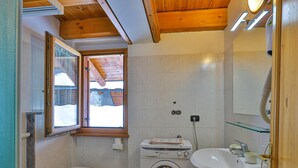 Ein kleines Badezimmer mit Toilette, Bidet, Waschmaschine und Waschbecken.