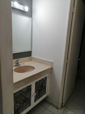A bathroom with a sink, mirror, and tiled cabinet.