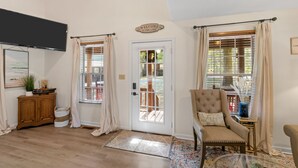 A room with a wooden cabinet, a television, a door with a window, and a chair.