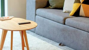 A modern living room with a grey sofa, a small wooden table, and a black floor lamp. - Chic CBD Townhouse | Walk to One NZ Stadium & SALT (Christchurch)