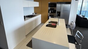 Cozinha moderna com ilha central, eletrodomésticos embutidos e vista para a cidade.
