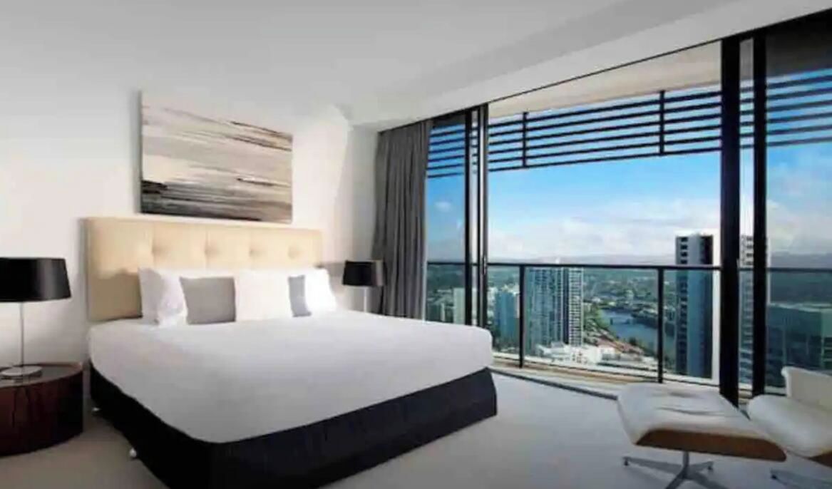 Ein modernes Hotelzimmer mit großem Bett, Blick auf die Stadt und einem Balkon.