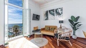 A spacious living room with a large window, a sofa, a coffee table, and a potted plant. - Splendid sea view apartment (Menton)