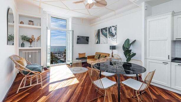 A spacious living area with a dining table, chairs, and a ceiling fan. There is a sofa and a view of the outdoors. - Splendid sea view apartment (Menton)