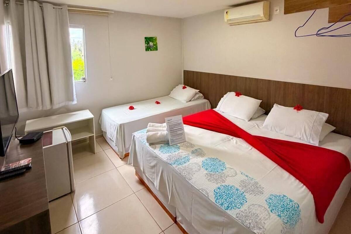 Una habitación de hotel con dos camas, un escritorio, un televisor y un aire acondicionado.