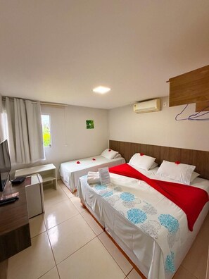 Quarto de hotel com duas camas, uma escrivaninha, uma televisão e um aparelho de ar condicionado.