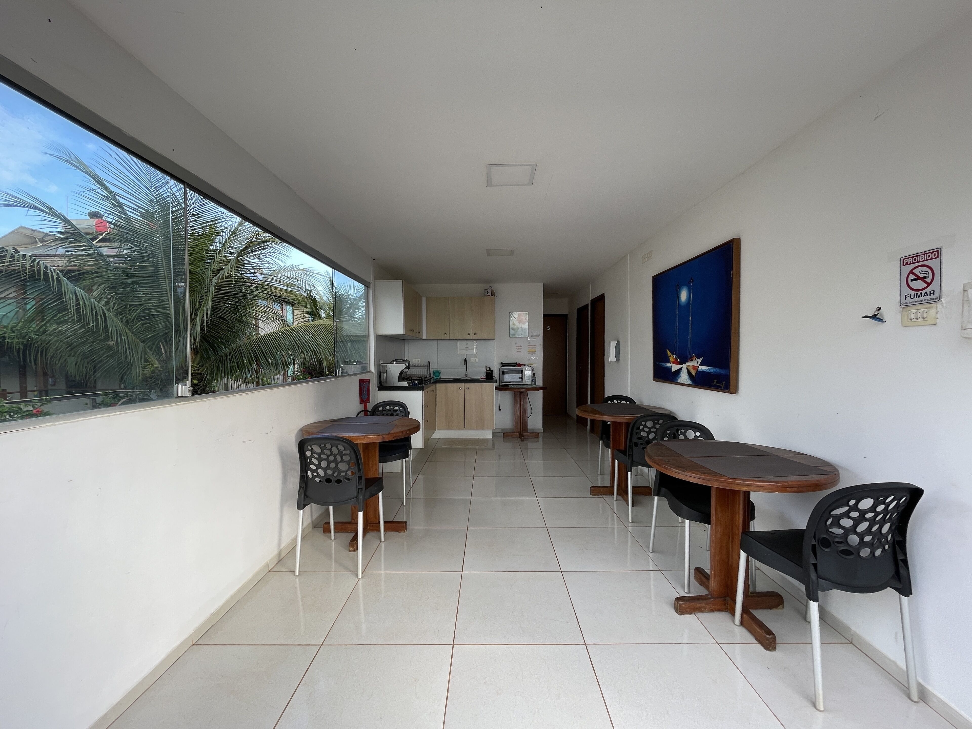 A modern apartment with a balcony, a kitchen, and a dining area with four chairs and a table.