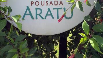 A circular sign with a silhouette of a person on a boat, surrounded by greenery and red flowers.