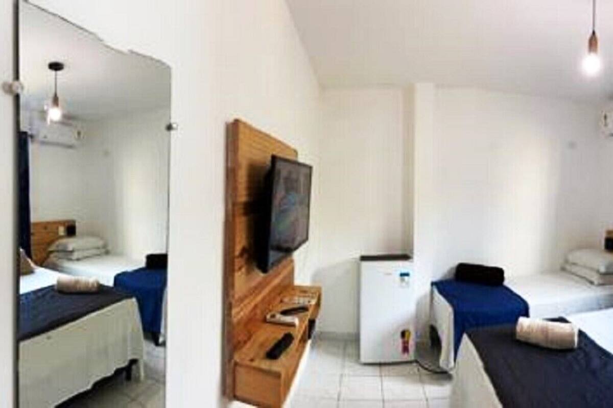 Un dormitorio con cama, mesitas de noche, un espejo y una ventana con cortinas.