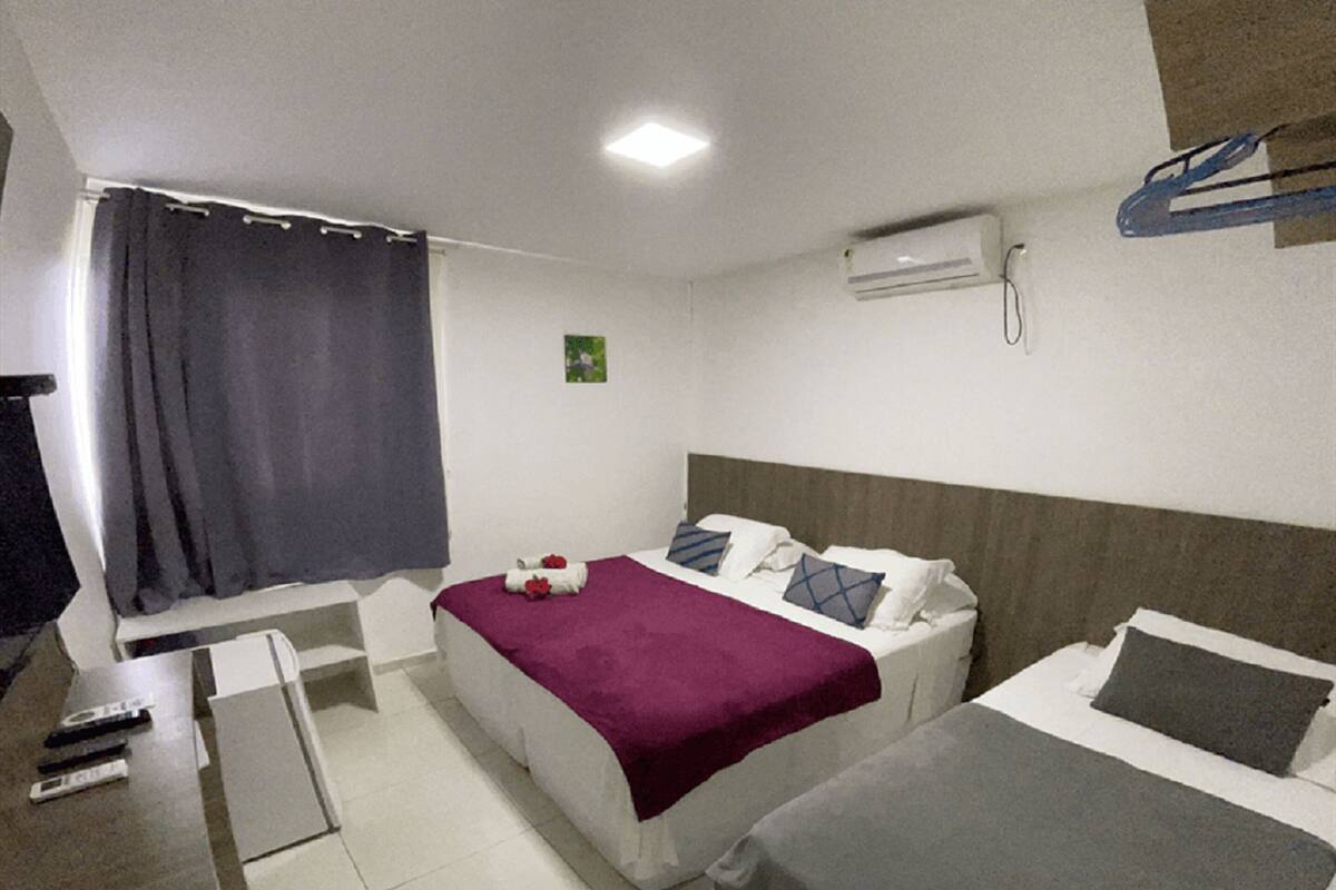 Habitación de hotel con dos camas, un escritorio, una silla, un televisor y aire acondicionado.