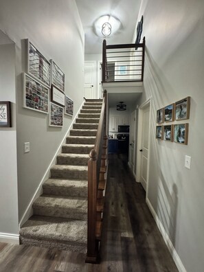 A staircase with a wooden handrail leading to a landing with a ceiling light fixture.