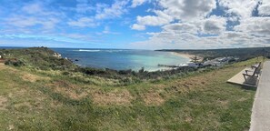 Un paysage côtier comprenant une plage, une jetée et un espace de stationnement.