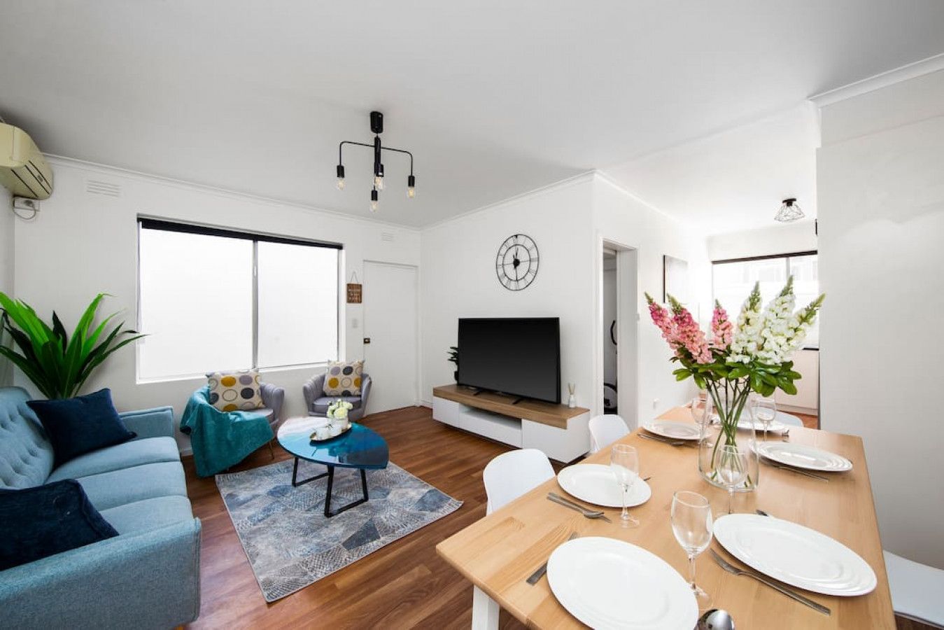 Un salon moderne avec un canapé, une table basse, un téléviseur et un coin repas avec une table mise pour deux personnes.